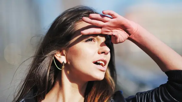 Woman shields sunlight with hand