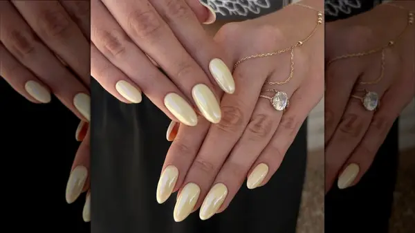 Hands with a butter yellow manicure with a chrome finish