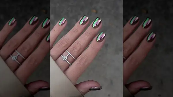 A hand with a shimmering green and purple chrome manicure
