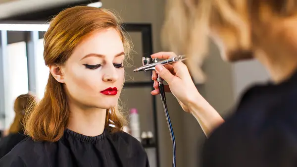 Woman applying airbrush foundation