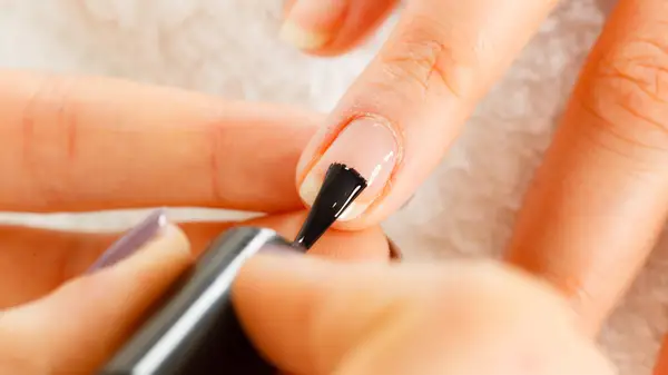 applying base coat polish to bare nail