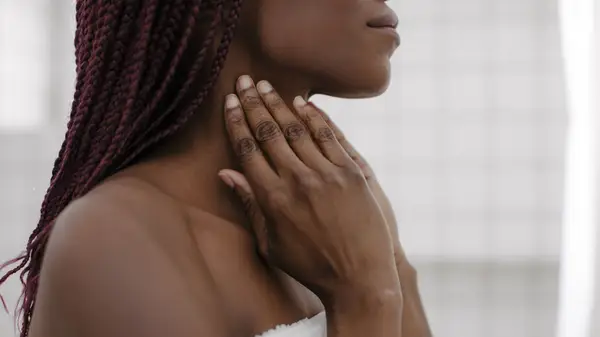 woman in towel touching neck