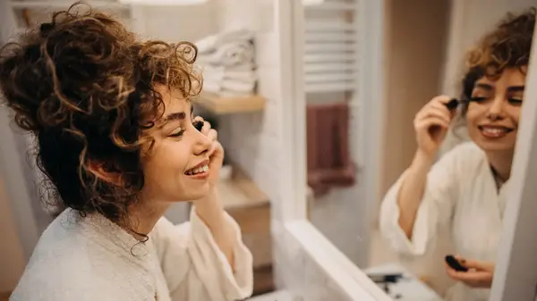 Woman applying mascara in mirror