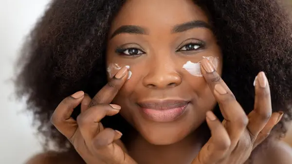 Woman applying facial moisturizer