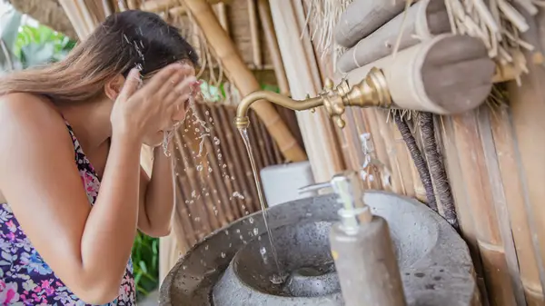 woman splashes water on face