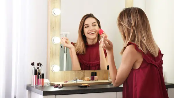 Womans hands with makeup sponge and fluffy brush