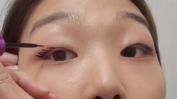 Woman drawing on lashes