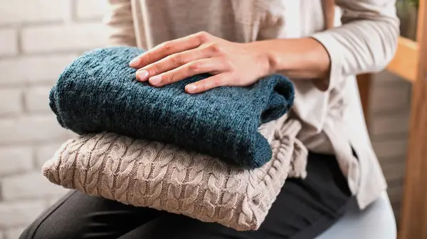 Woman holding sweaters
