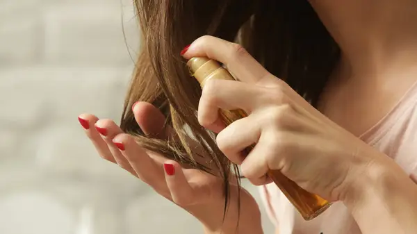 A woman applying hair oil