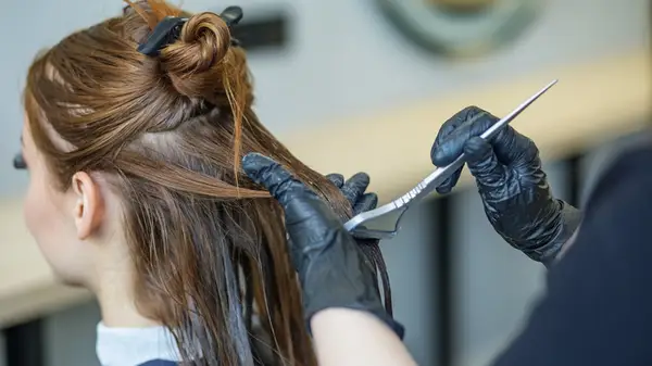 Hairdresser applies hair color to client