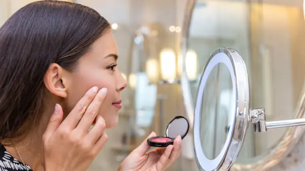 Woman applying blush to cheeks