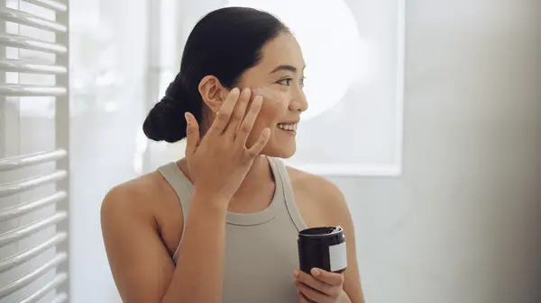 Woman applying skincare from jar