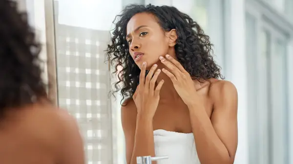Woman popping pimple in mirror