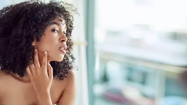 Woman examining face in mirror