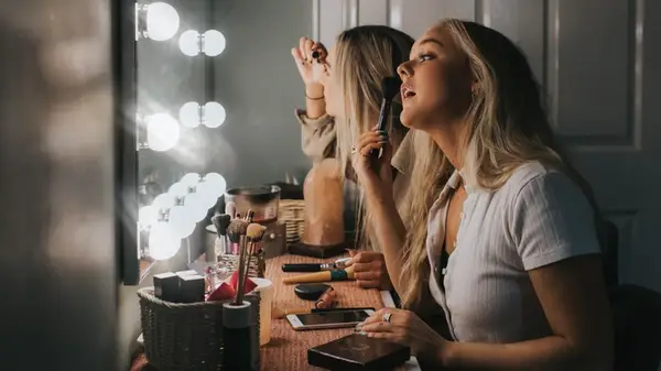 Woman applying makeup in front of a mirror