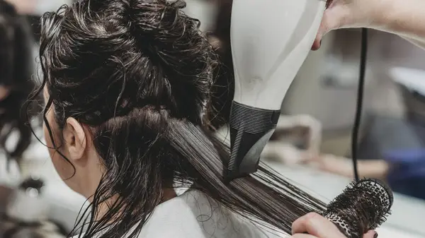 woman blow drying sections of hair