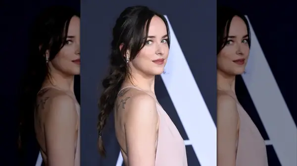 Dakota Johnson on the red carpet in a pink gown with a thick braid