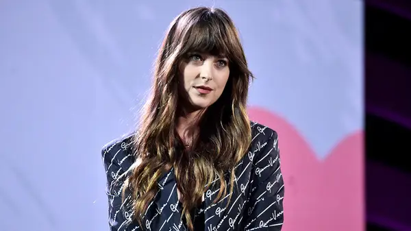 Dakota John on stage in a black suit covered in white writing