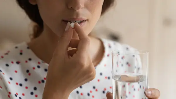woman swallowing pill with water
