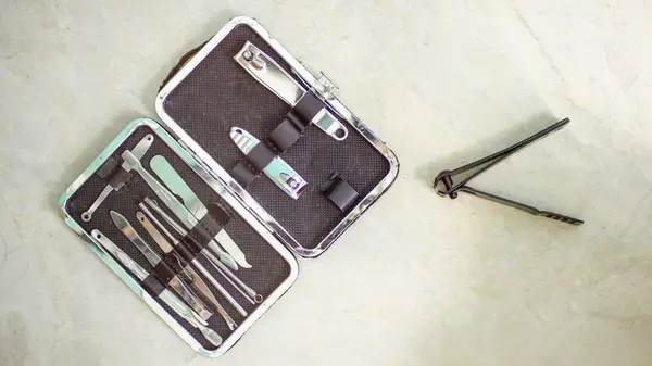 Nail clipper kit open on a counter with pair of clippers resting beside it
