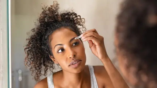 Woman tweezing eyebrows