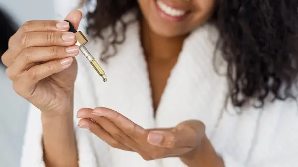 Black woman applying cuticle oil