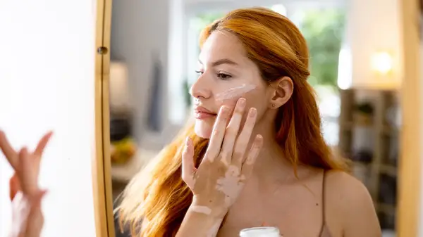 Woman applying lotion on face