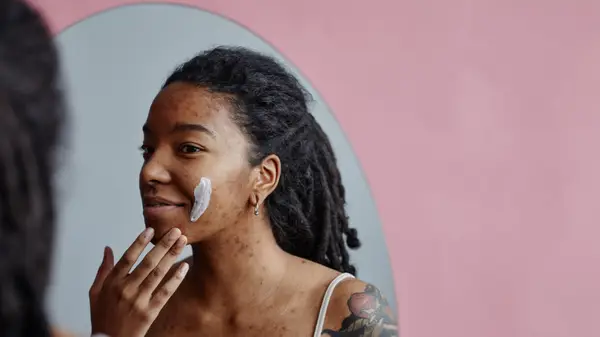 Woman applying ointment on face