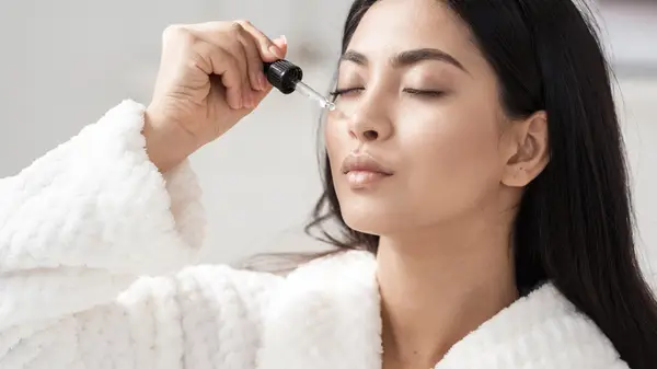 Woman applying hyaluronic acid serum 