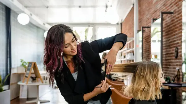 A hair stylist cuts a client