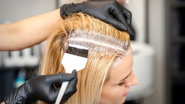 A stylist adds a root touch up on a client