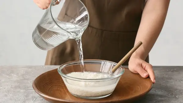 Someone adding water to bowl of rice