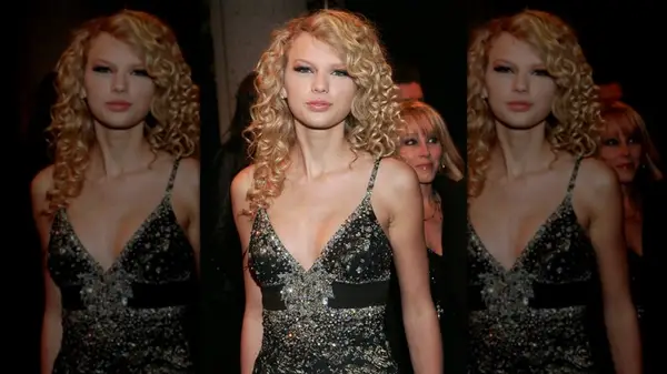 Taylor Swift looking into the camera while wearing a sparkly dress and wearing her hair in her natural curls