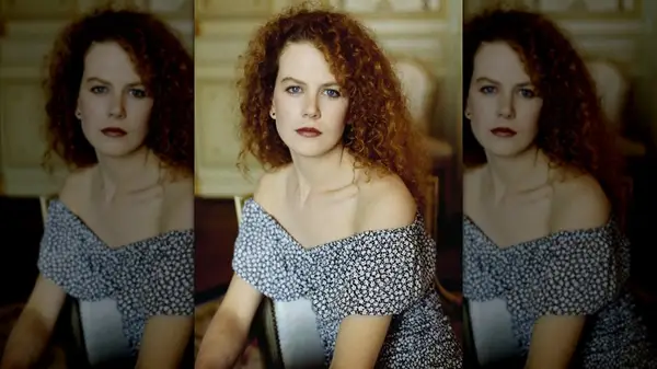 Nicole Kidman sitting in a chair and posing for a photo while wearing her red hair down with natural curls