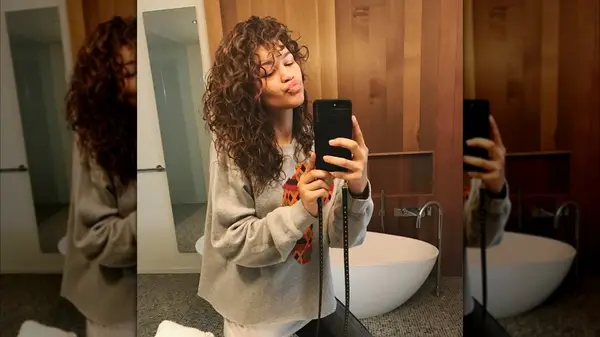 Zendaya posing for a mirror selfie while wearing her hair in natural curls