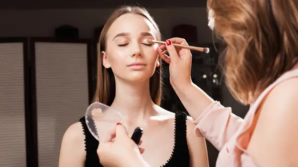 Makeup artist priming client