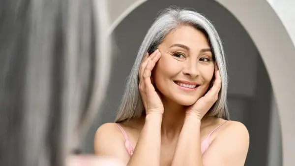 woman looking wrinkles in mirro