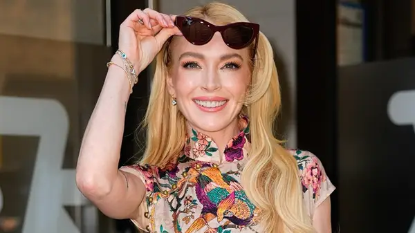 Lindsay Lohan smiling and lifting up her sunglasses