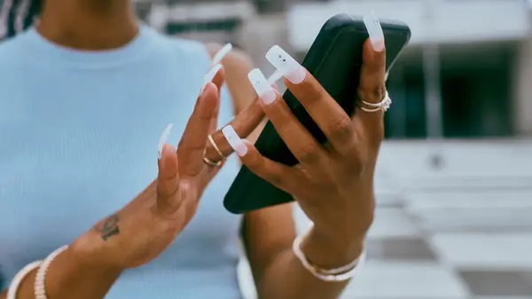 Person with long acrylic nails on her phone