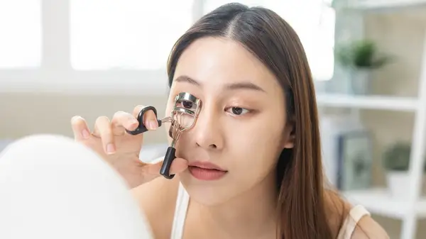 Woman curling eyelashes