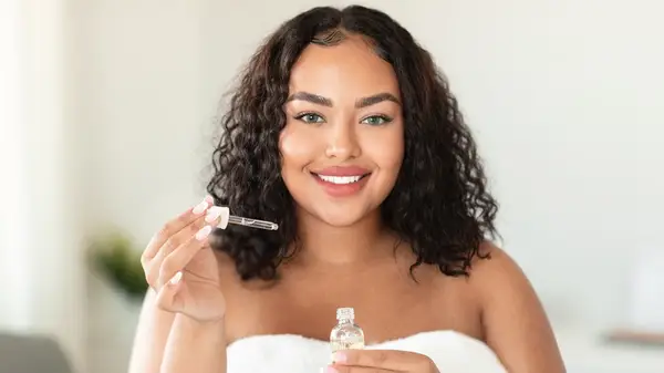 Woman smiling holding serum eyedropper
