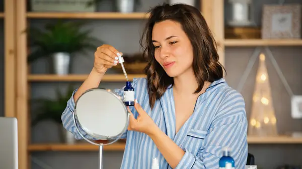 Woman holding eyedropper over bottle