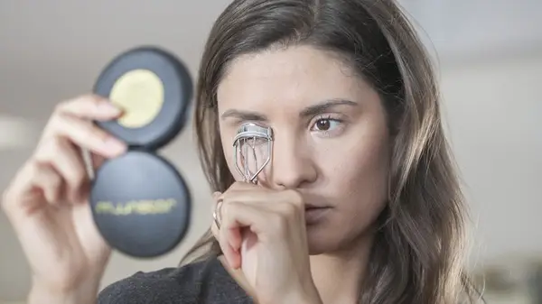 A woman curling her eyelashes