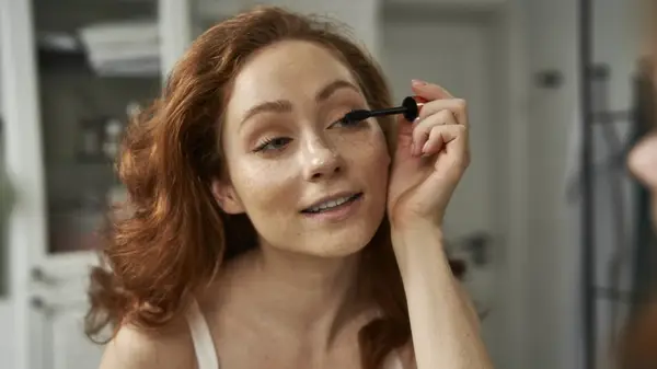 A woman applying mascara