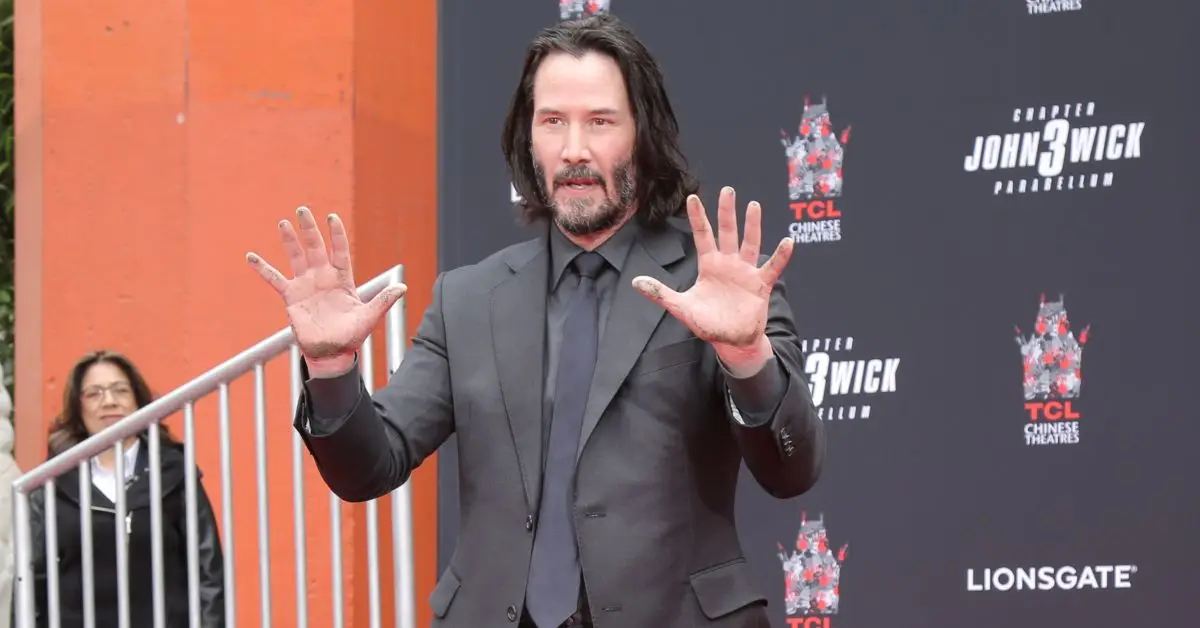 Keanu Reeves hält seine Hände hoch, als würde er kapitulieren