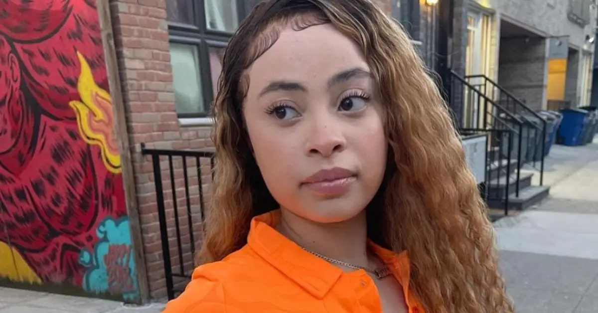 Ice Spice con un vestido naranja parada frente a un edificio