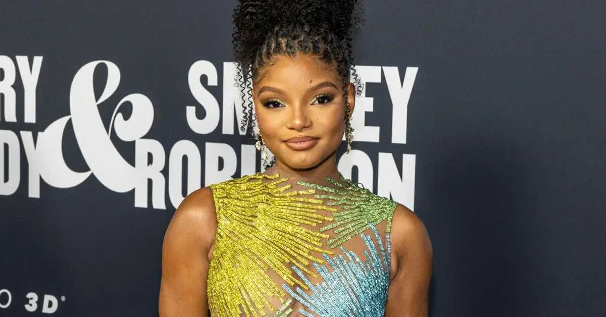 Halle Bailey debout dans une robe verte et bleue
