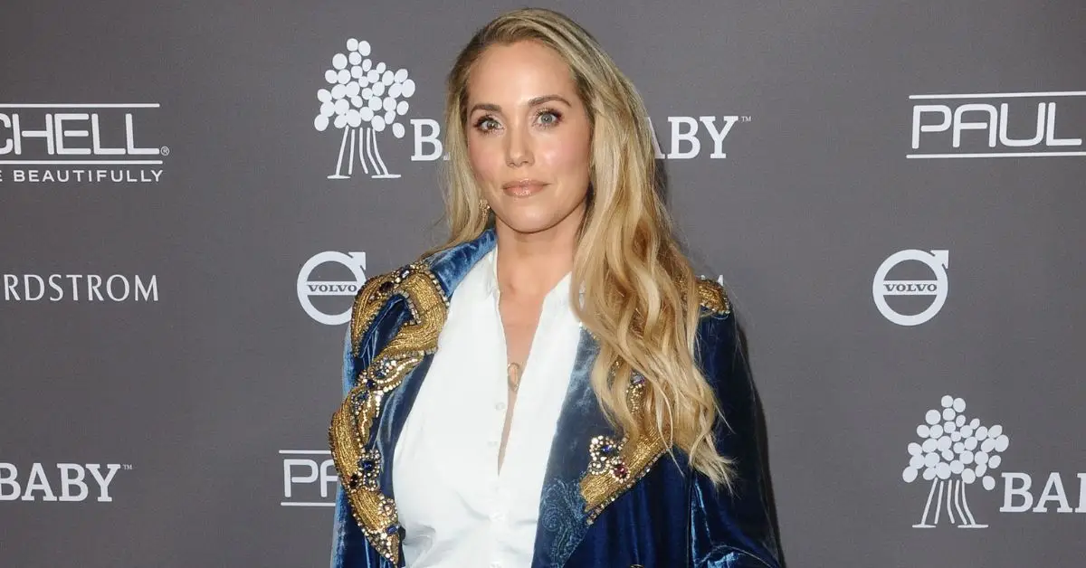 Elizabeth Berkley no tapete vermelho vestindo um blazer de camurça.