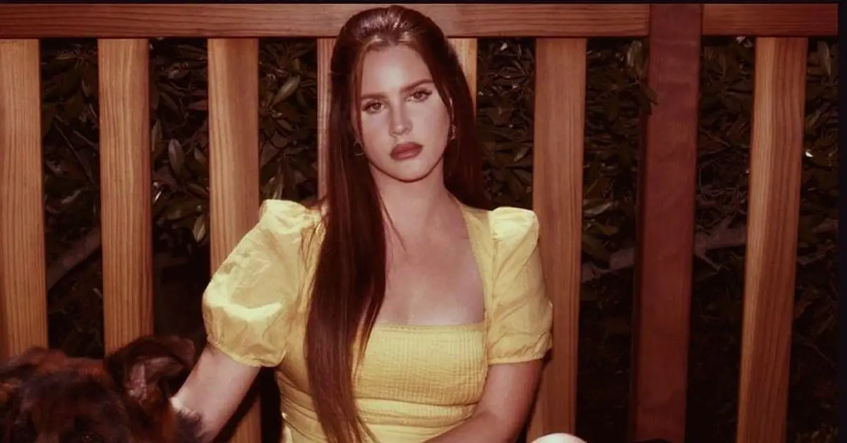 Lana Del Rey w żółtej sukience siedzi na patio