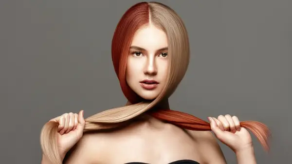 Woman with two-toned hair color, one side red, the other a darker blonde